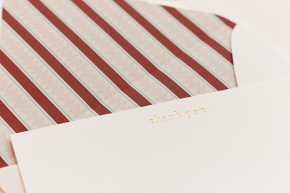 Striped envelope with a 'thank you' card on a matching background